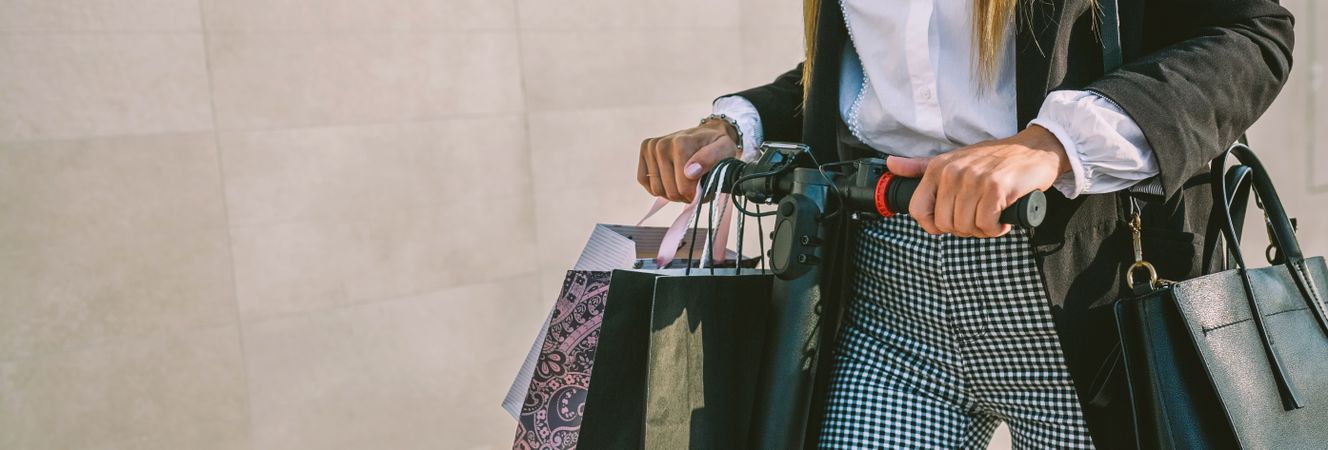 Unrecognizable woman with shopping bags on electric scooter