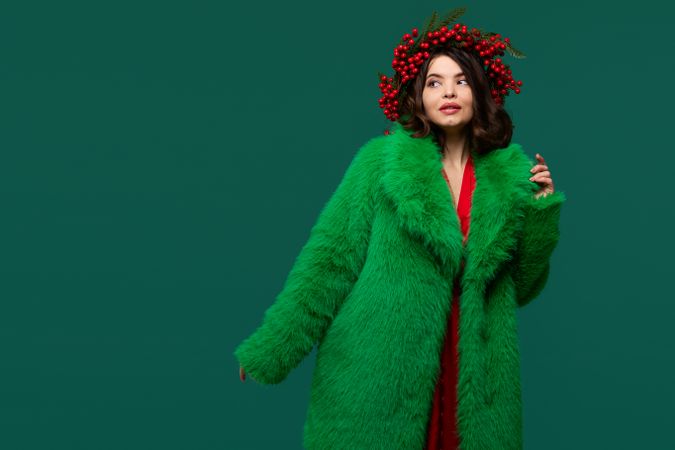 Woman in green faux fur coat and red berry wreath