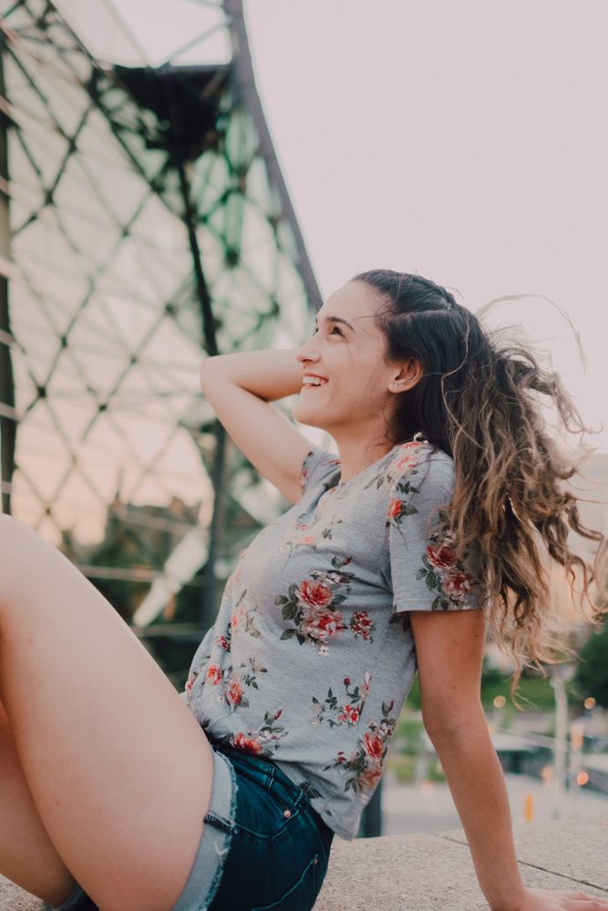 Smiling modern woman sitting on parapet