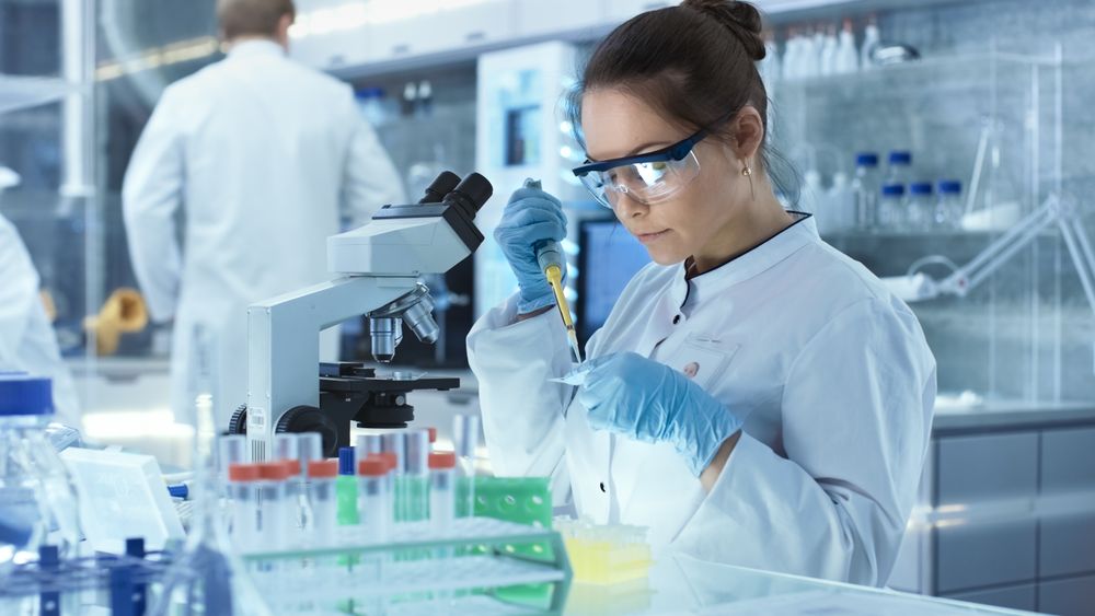 Female Research Scientist Uses Micropipette Filling Test Tubes in a Big Modern Laboratory.