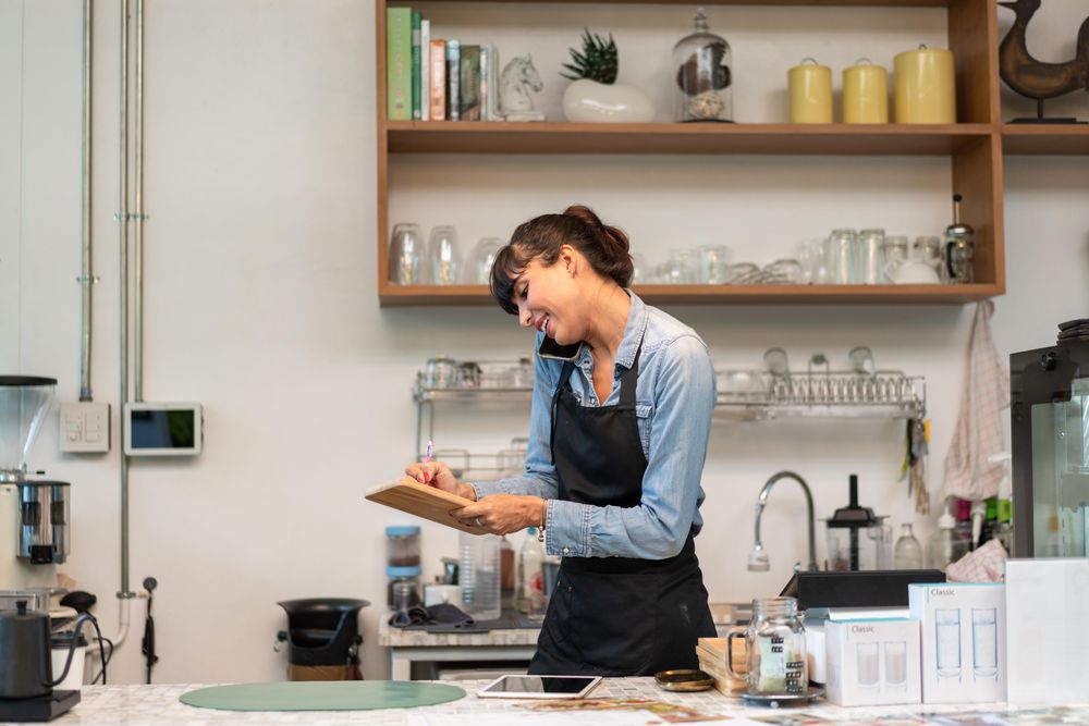 Woman on phone in cafe writing down order