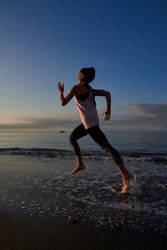 Woman running on wet seashore on evening time