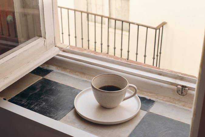 Cup of coffee on vintage in ceramic mug checkered tile windowsill