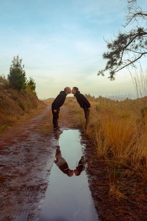 Men hugging and kissing near water puddle