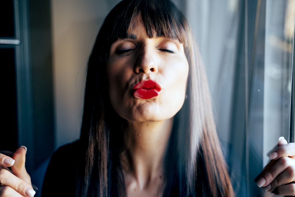 Stylish woman kissing glass
