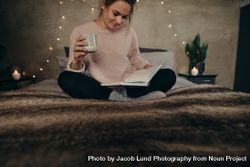 Relaxed woman on bed reading book with coffee 5pg3E8