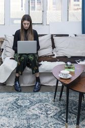 Woman sitting on sofa and using laptop