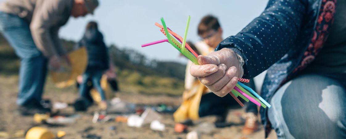 Woman showing handful of straws collected on the beach
