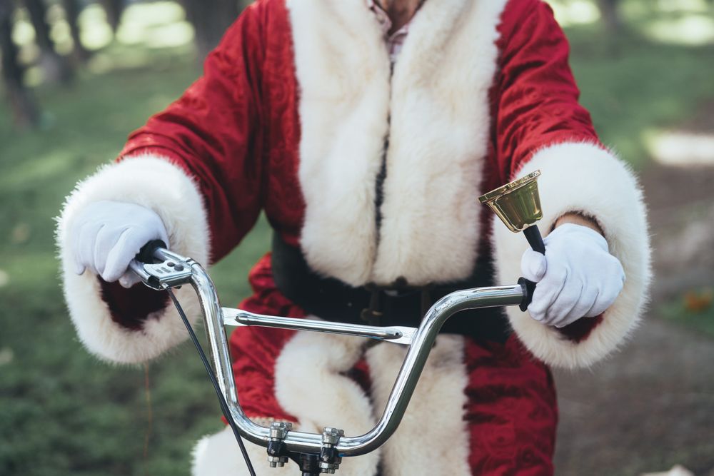 Happy Santa Claus riding bicycle by van