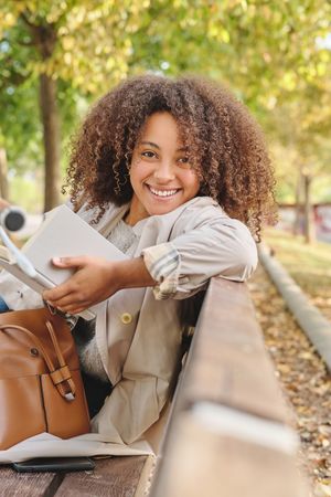 Smiling Black woman with book in park