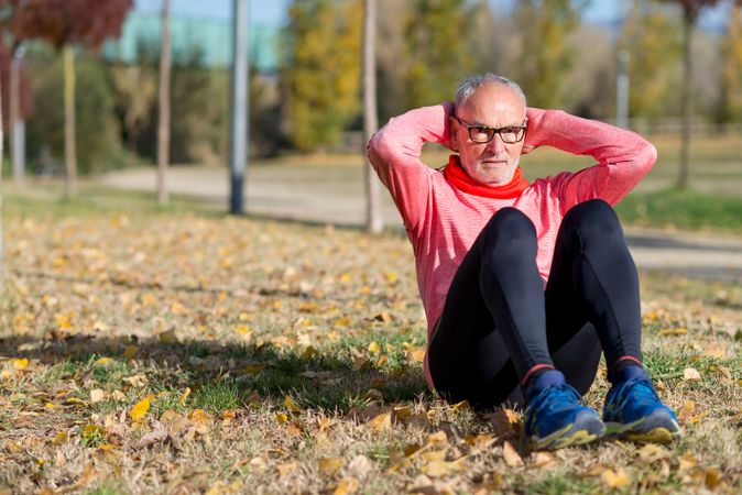 Older male with grey hair doing sit ups in park