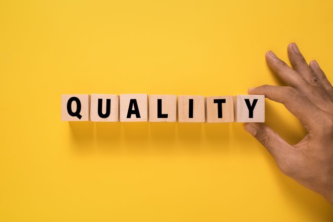 quality word on wooden blocks isolated on yellow background
