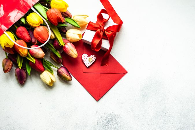 Tulips in shopping bag with present and card on grey counter