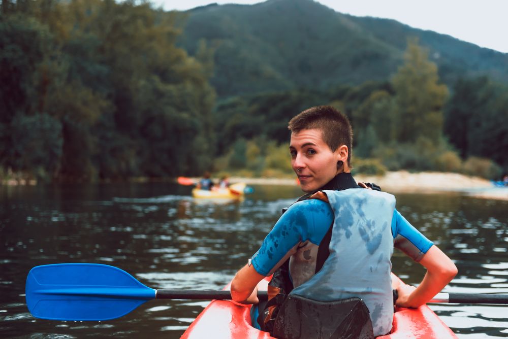 Female kayaking with paddle in raised hands