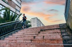 Female training running down stairs with dusk clouds