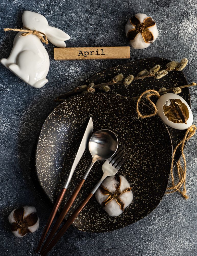 Top view of Easter table setting with cotton in dark bowl with rabbit & egg decor