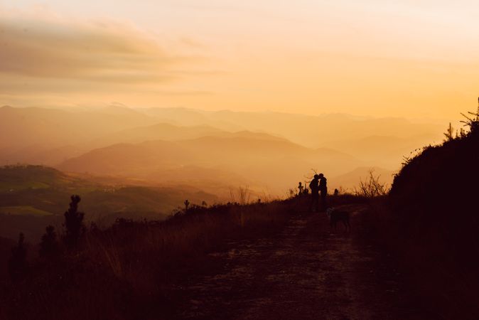 Men hugging near dog on road on hill