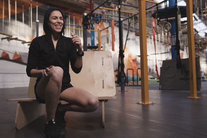 Smiling woman with energy bar in gym