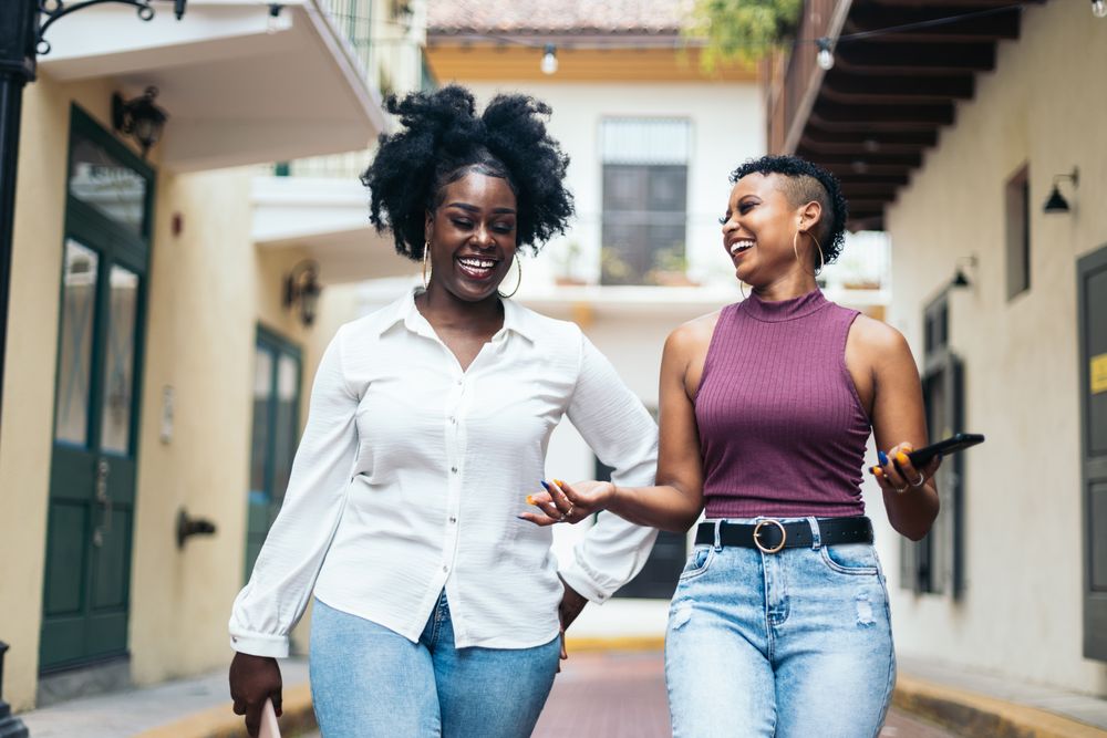 Happy women using mobile while walking in the city