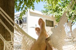 Anonymous male traveler chilling in hammock in countryside