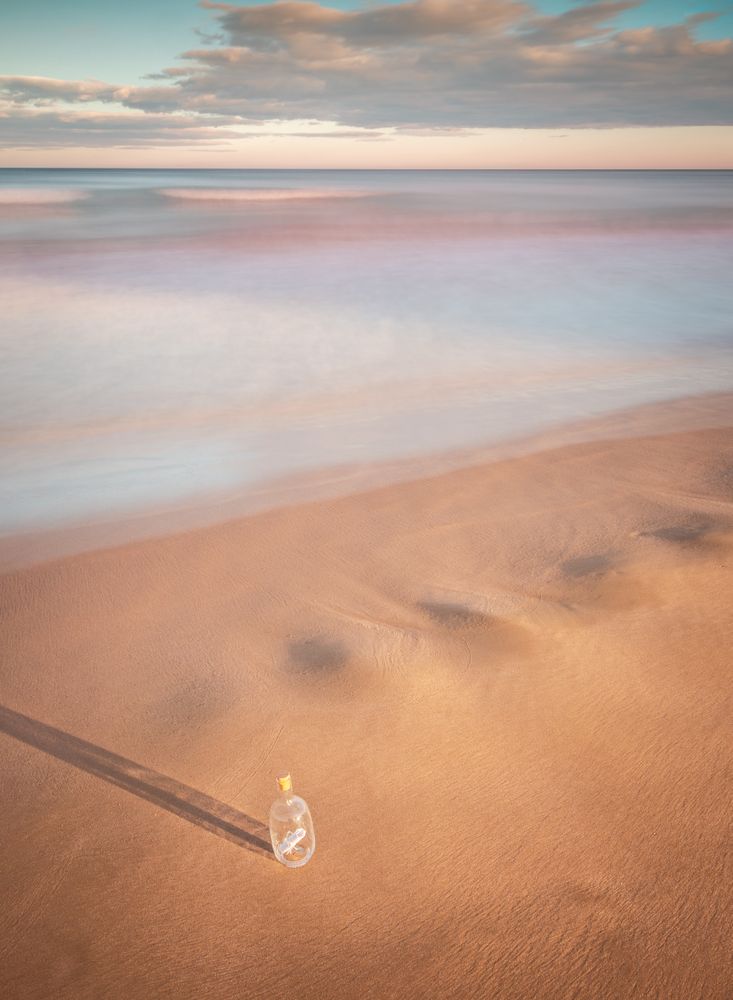 Bottle in sand near sea