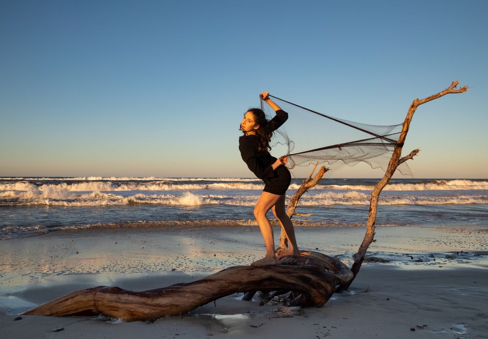 Woman in fishing net fixed on twig near water on shore
