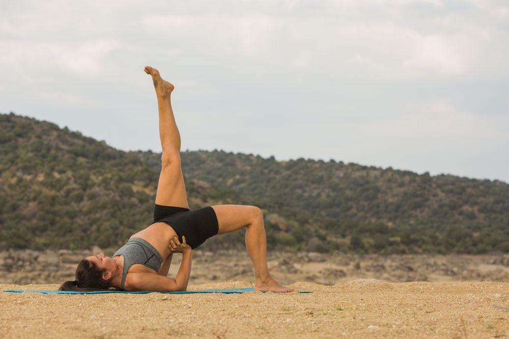 Woman practicing yoga outdoors near water