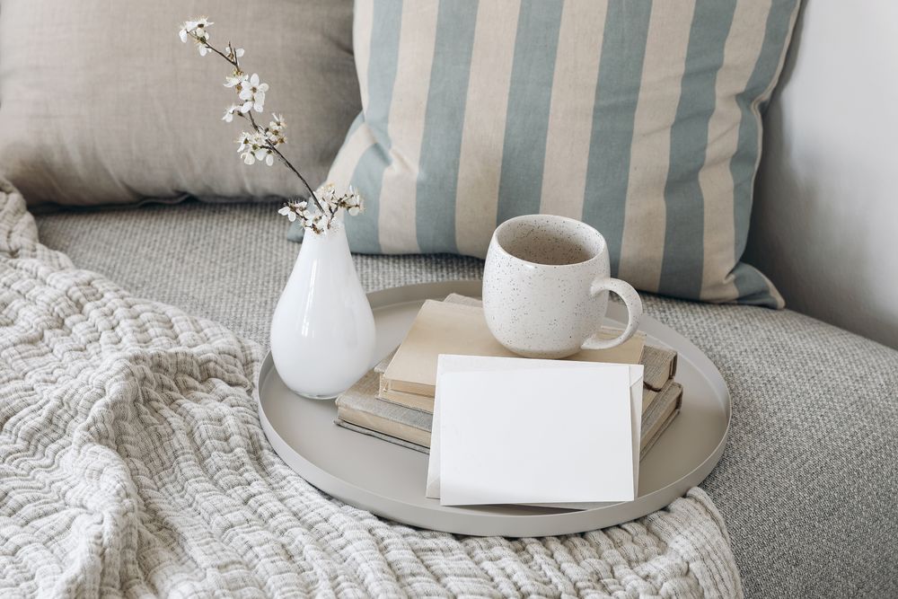 Stylish interior still life with cup of coffee, tea on pile of books on tray with mock up card