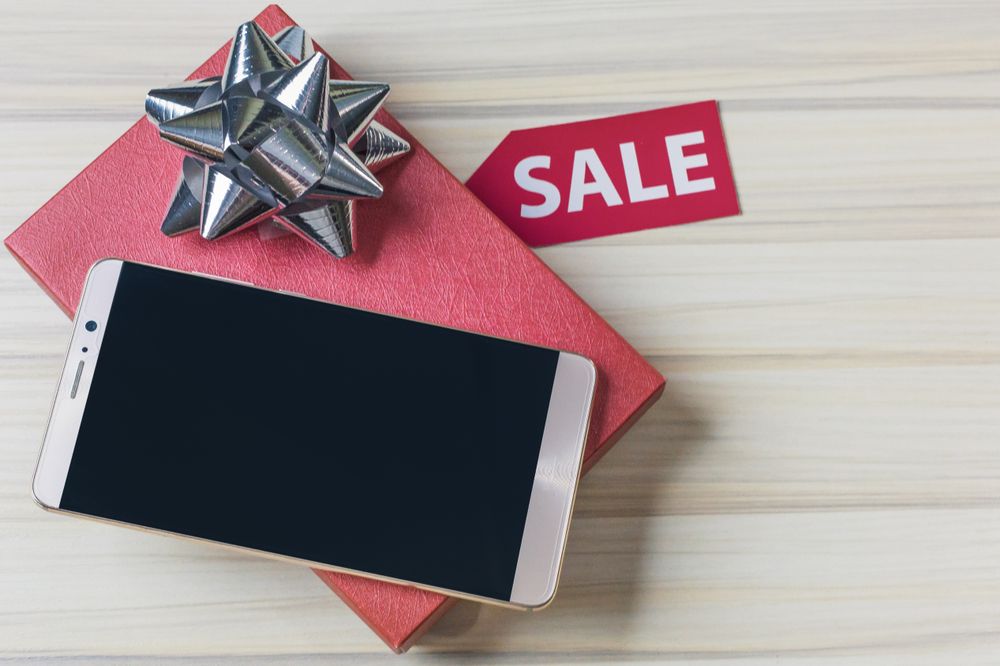 Smartphone Displayed on a Gift Box With Decorative Bow and Sale Tag