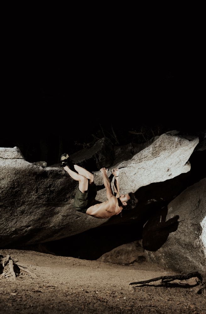 Man practicing rock climbing among large rocks in a forest