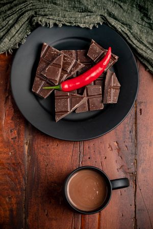 Hot beverage near plate with chocolate and pepper