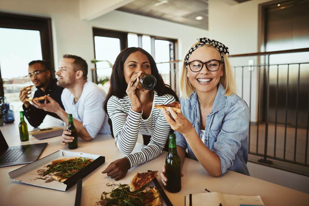 Two young businesswomen enjoying pizza lunch at work