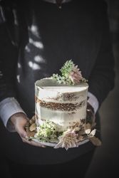 Smiling woman holding plate with cake decorated by flowers and plants
