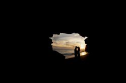 Woman and man embracing in cave on seashore in darkness