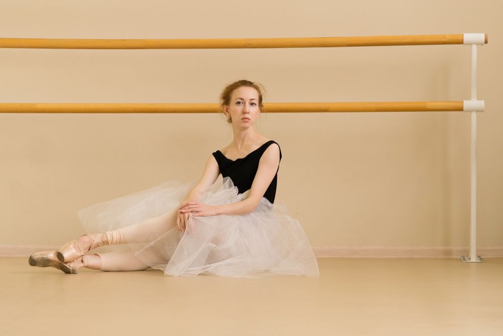 Ballet dancer sits on the floor in dance studio