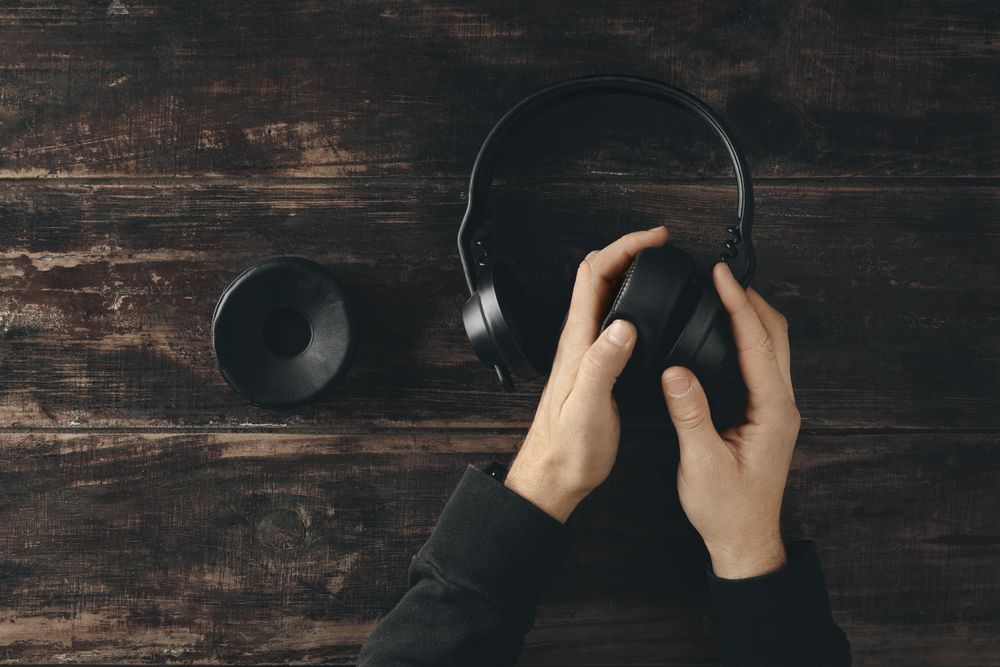 Hands repairing headphones on wooden table