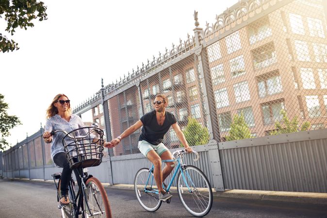 Smiling couple holding hands while cycling