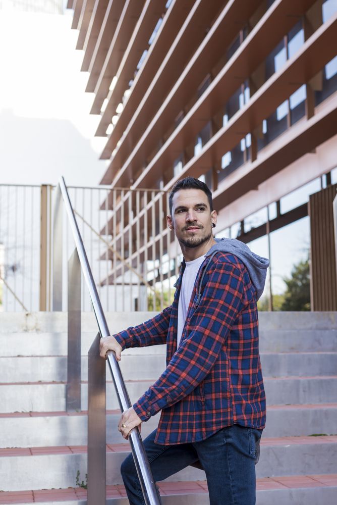 Smiling man in plaid shirt walking up stairs on a sunny day