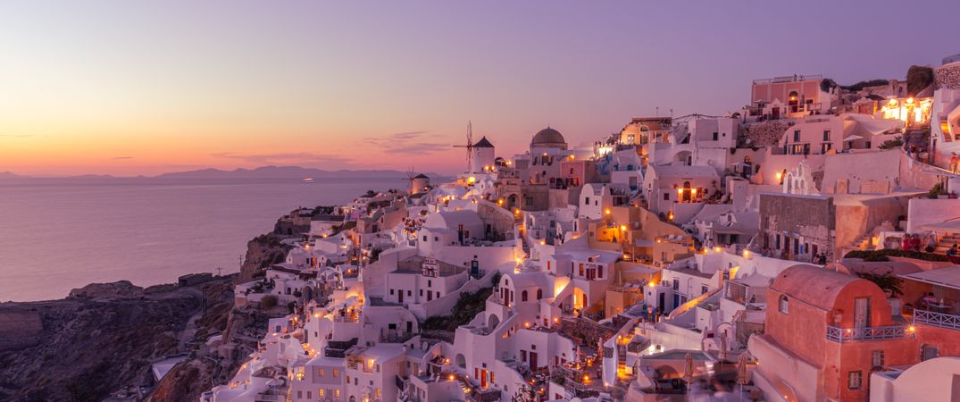 Wide shot of buildings on a cliff overlooking the sea at sunset