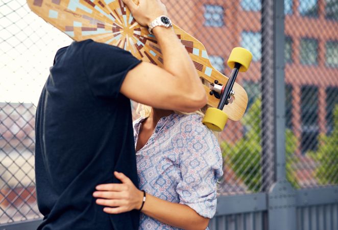Cute couple hiding behind a skateboard