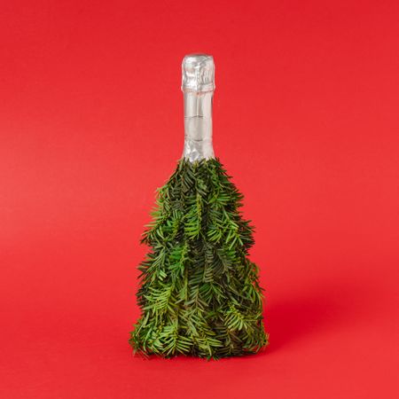 Champagne bottle Christmas tree concept on red background