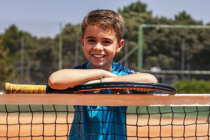 Little boy playing tennis on a dirt court