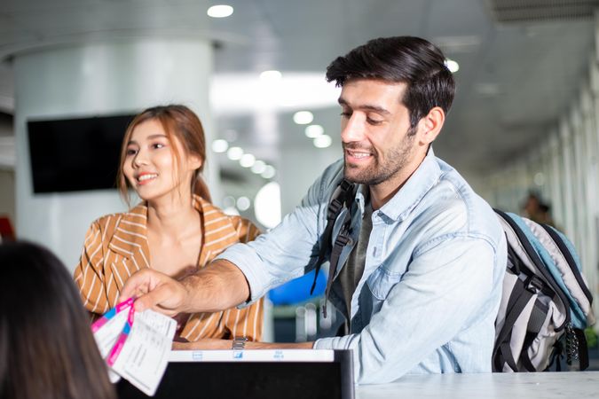 Man checking in for flight at airport with girlfriend