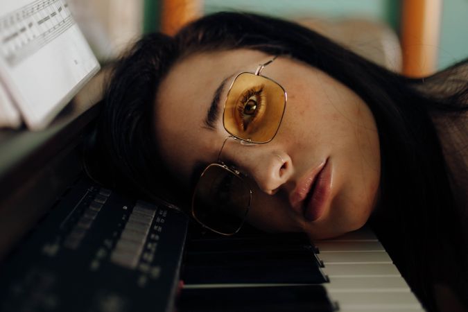 young woman with her head resting on the piano