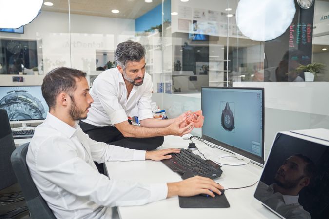 Men designing respirator on computer