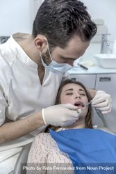A portrait of a dentist examining female mouth, vertical 0L6AP4
