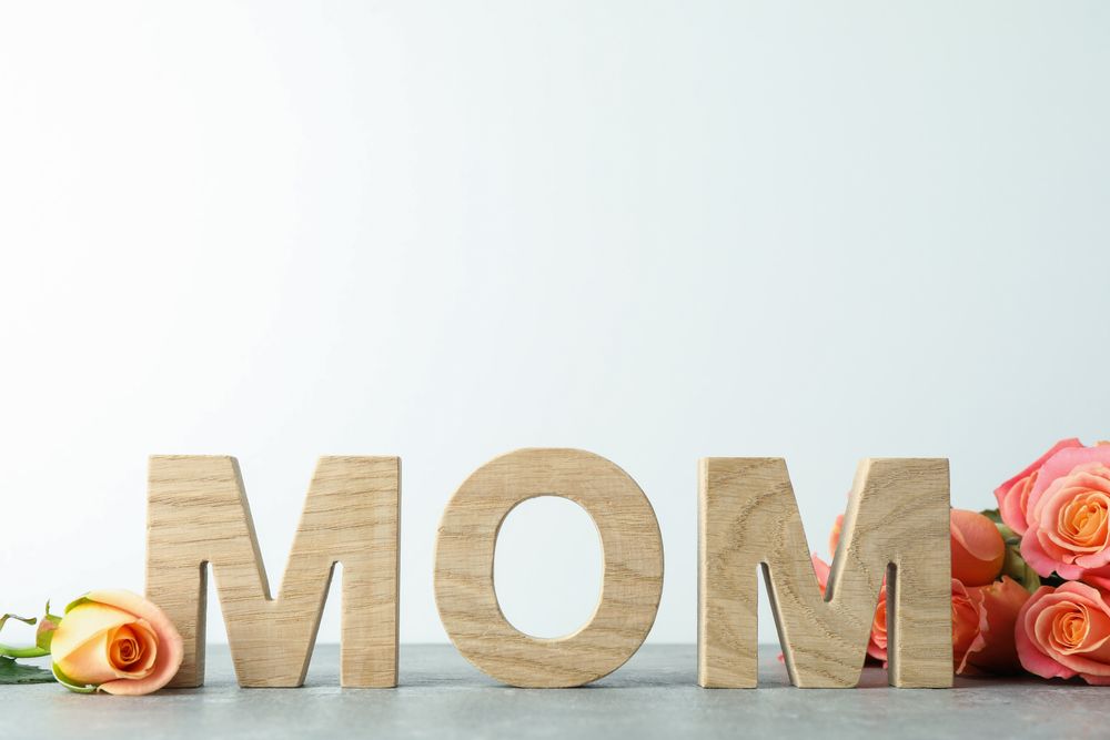 Inscription Mom, beautiful pink roses on grey table, space for text