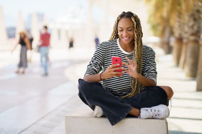 Content woman checking mobile phone while sitting in pedestrian area outside