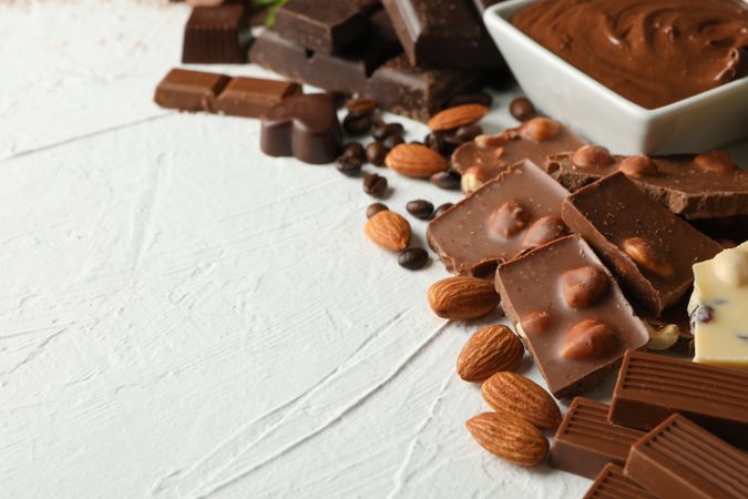 Chocolate, melted chocolate, coffee and almond on light background