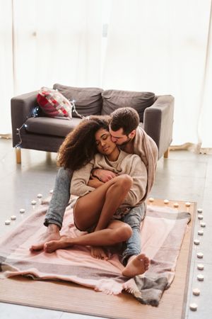 Multiethnic couple hugging on floor at home